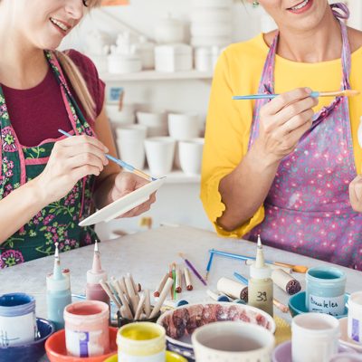 Two,Women,Painting,Own,Ceramic,Tableware,In,Diy,Workshop,With Two women painting own ceramic tableware in DIY workshop with brushes